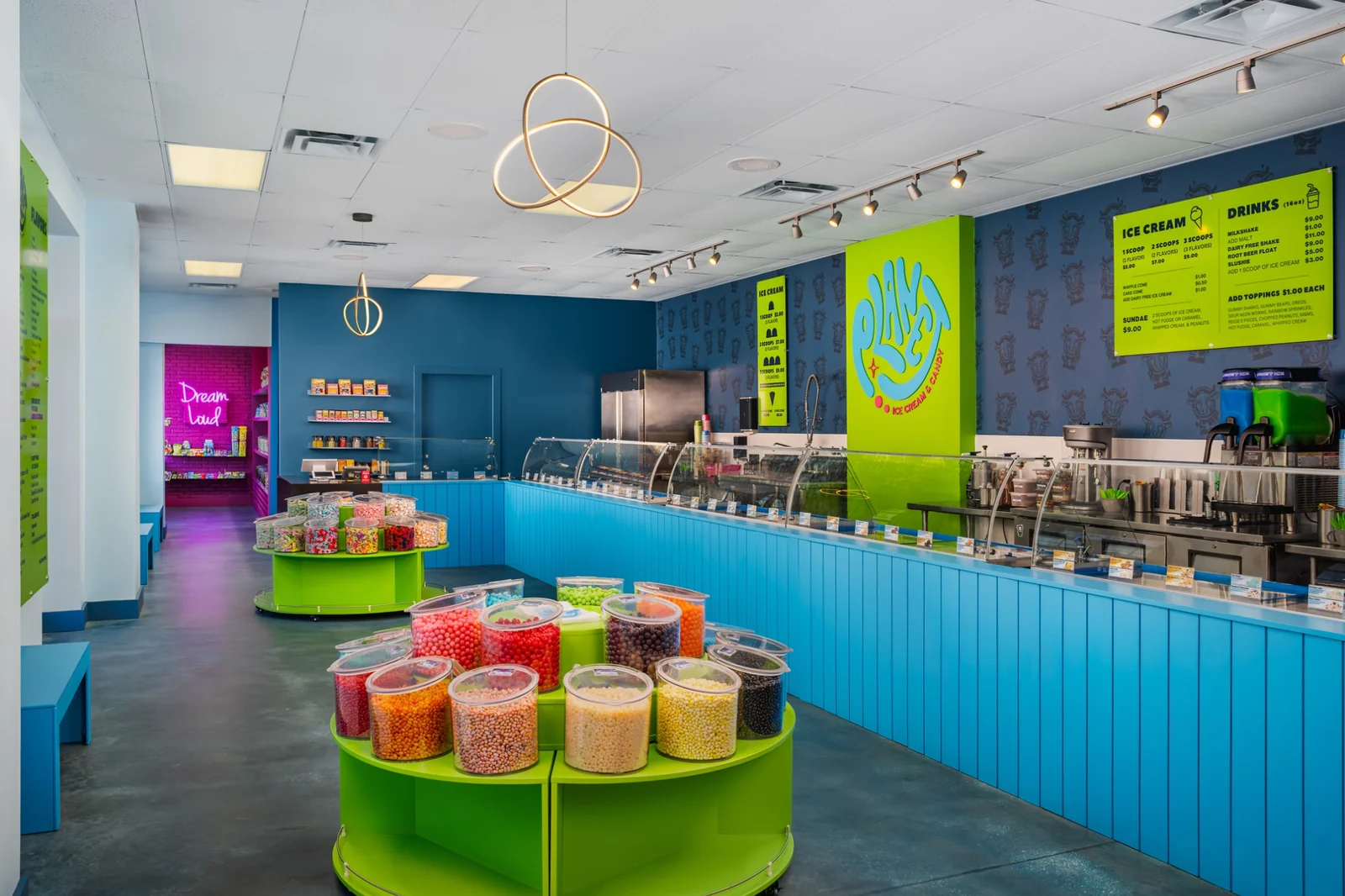 Interior of Planet with turquoise ice cream cases, lime-green candy displays, and a large Planet logo on the back wall.