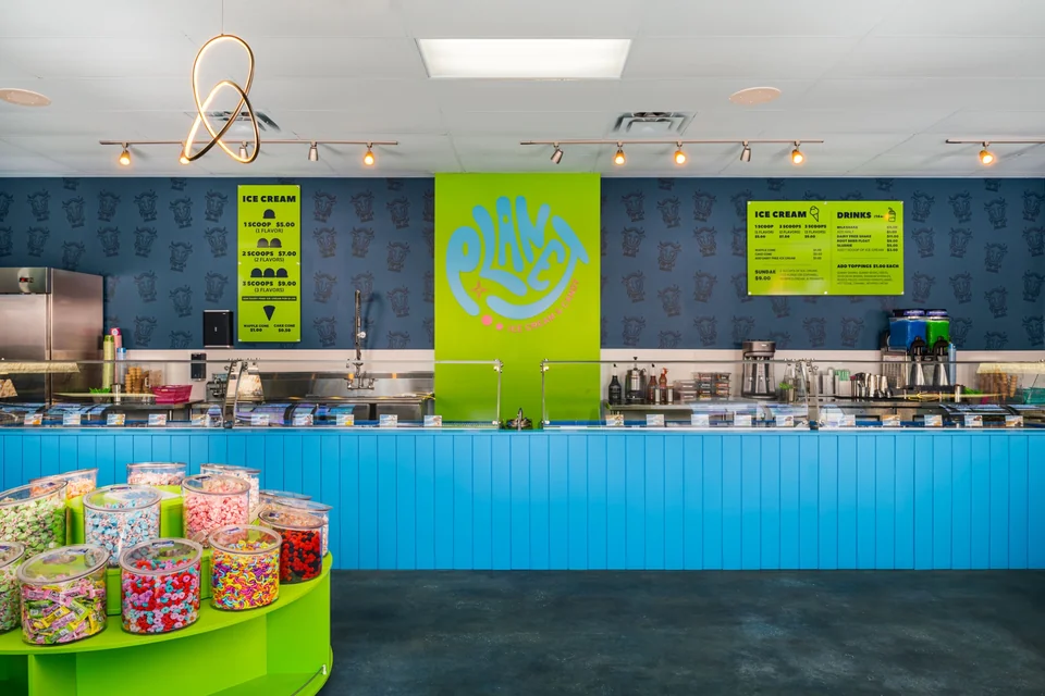 A front view of Planet’s turquoise ice cream counter, green candy displays, Planet wall logo, and lime-green menu boards.