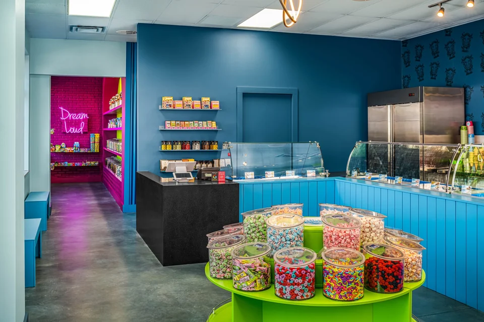 Clear jars of colorful candy on a lime-green display in front of Planet’s turquoise ice cream cases.