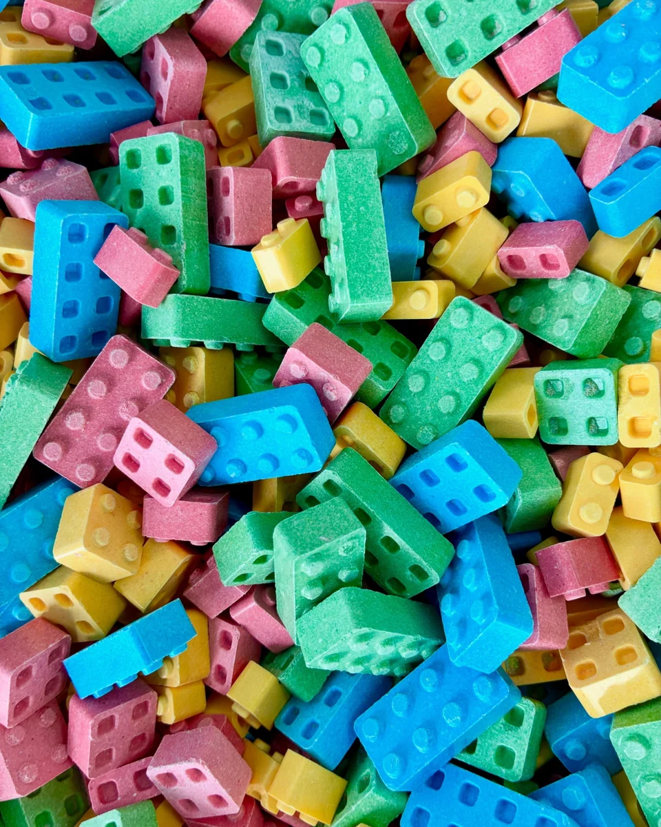 A close-up of pink, green, blue, and yellow candy pieces shaped like toy building bricks.