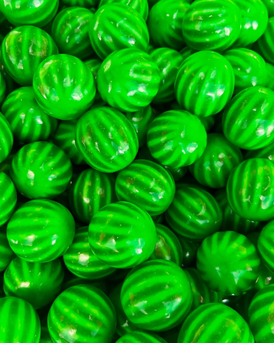 Glossy round green candies with dark stripes, resembling miniature watermelons.