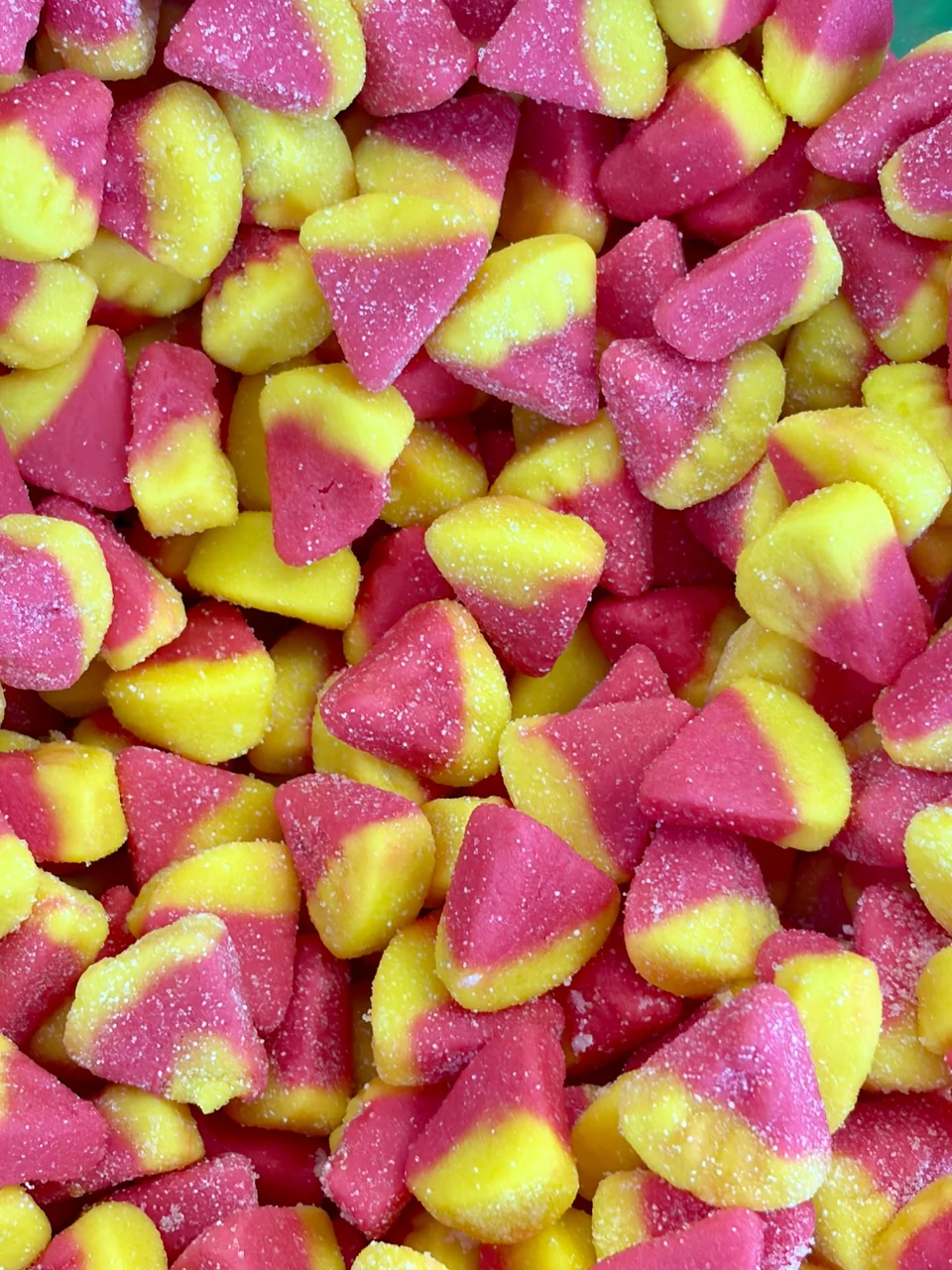 A close-up of sugar-coated pink and yellow gummies.